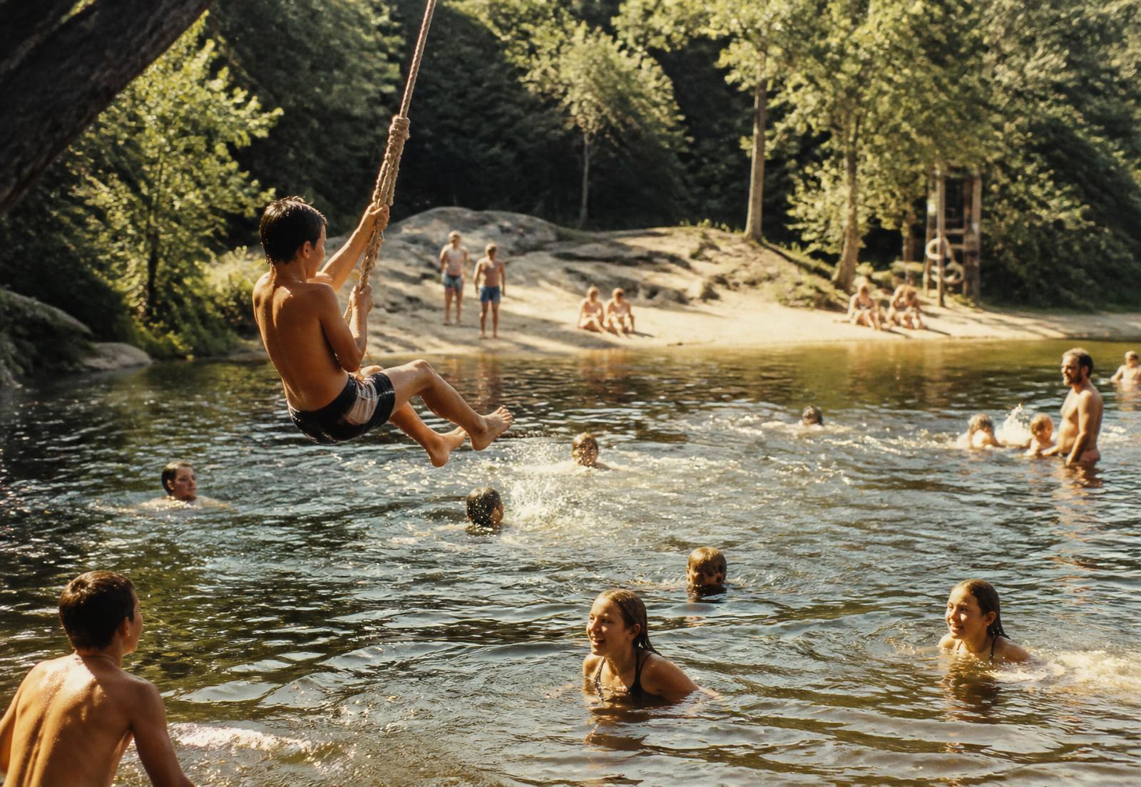Kids and adults swimming and playing at the pond